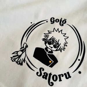 Op de afbeelding: Zwart-witte illustratie van een personage met stekelig haar dat een schooluniform en een zonnebril draagt. Het personage wordt omringd door een cirkel met de tekst "Gojo Satoru" in een gestileerd lettertype.