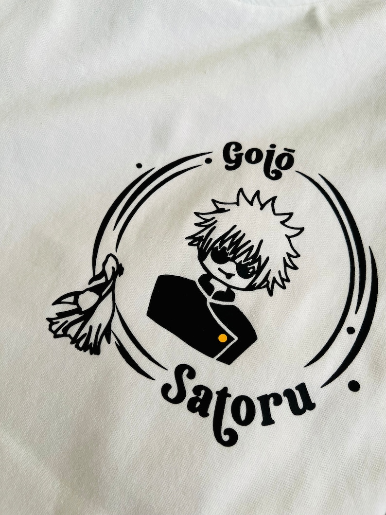 Op de afbeelding: Zwart-witte illustratie van een personage met stekelig haar dat een schooluniform en een zonnebril draagt. Het personage wordt omringd door een cirkel met de tekst "Gojo Satoru" in een gestileerd lettertype.