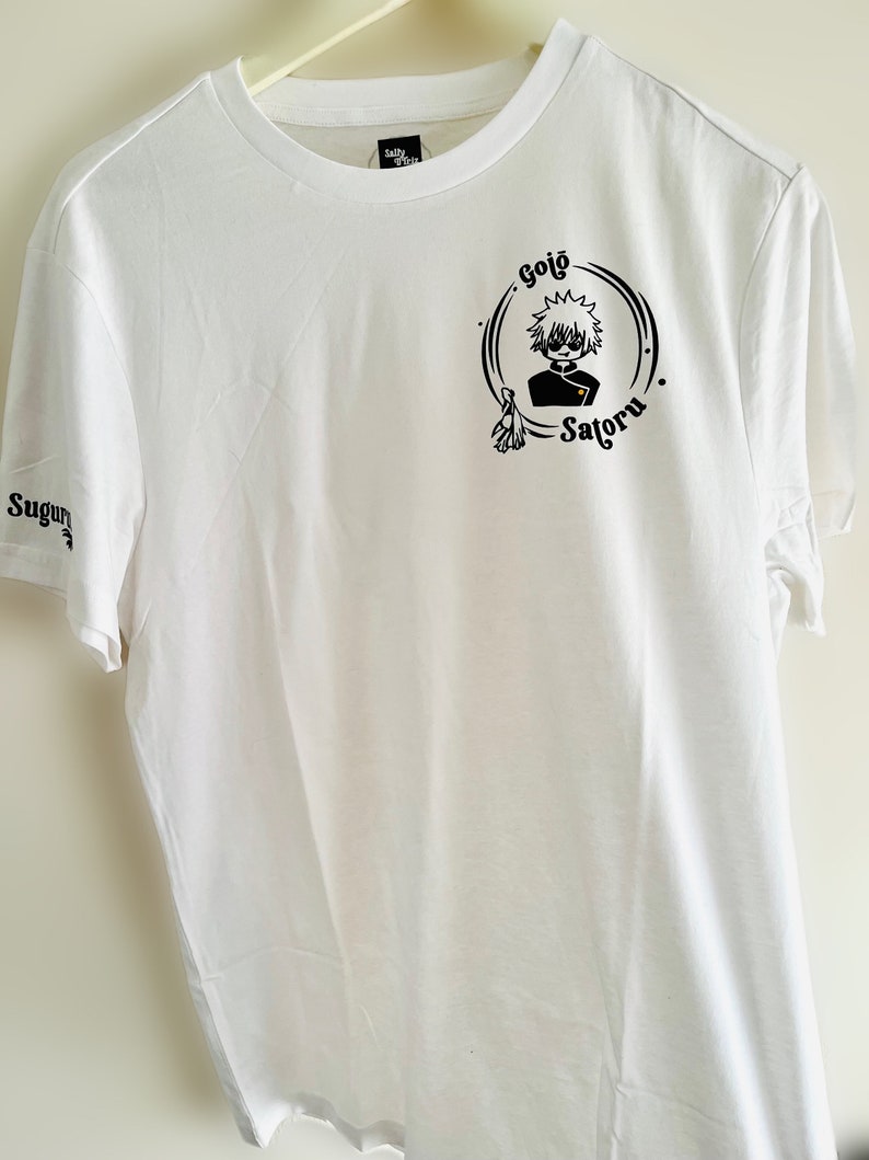 Op de afbeelding: Wit T-shirt met een zwart-witte grafische print van een personage met de tekst "Gojo Satoru".