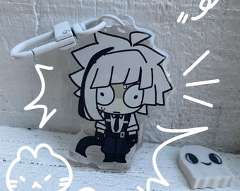 May include: A white and black anime character keychain with a white ghost charm. The character has short, spiky hair and is wearing a black and white outfit. The keychain is attached to a silver metal ring.