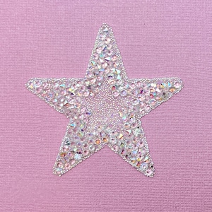 May include: A sparkly silver star-shaped embellishment on a pink background.