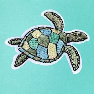 May include: A colorful embroidered patch of a sea turtle with a green, blue, and yellow shell. The turtle is swimming to the right.