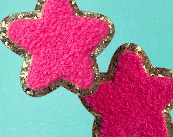 May include: Two pink fuzzy star-shaped patches with gold glitter trim.