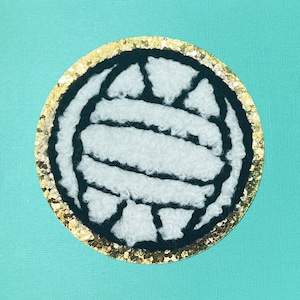 May include: A white volleyball with black stitching is surrounded by a gold glitter circle.