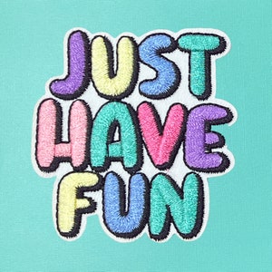May include: A colorful embroidered patch with the text "Just Have Fun" in bubble letters. The letters are outlined in black and have a white background.
