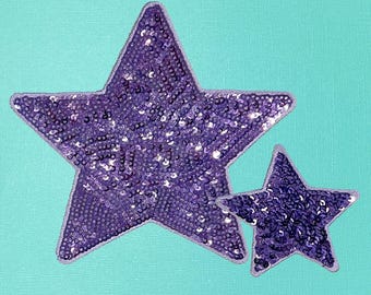 May include: Two purple sequined stars on a turquoise background. The larger star is in the foreground and the smaller star is behind it.