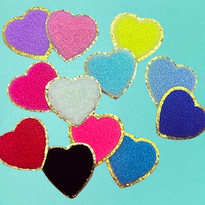 May include: Ten heart-shaped patches with gold trim. The patches are made of different fabrics and colors, including pink, blue, red, white, and black.