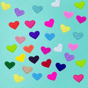 May include: A turquoise background with a variety of colorful felt hearts. The hearts are in different sizes and shapes, and they are arranged in a random pattern.
