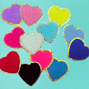 May include: Ten heart-shaped patches with gold trim. The patches are made of different fabrics and colors, including pink, blue, red, white, and black.