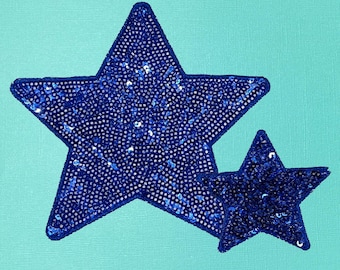 May include: Two blue sparkly star-shaped patches on a turquoise background.