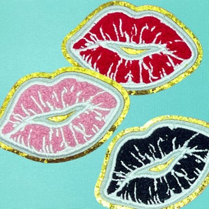 May include: Three embroidered lips patches with gold glitter trim. The lips are red, pink, and black.