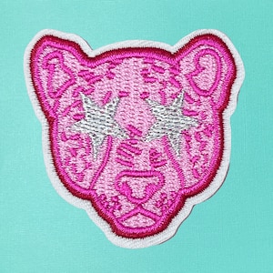 May include: Pink embroidered iron-on patch of a cartoon panther with silver glitter stars for eyes.
