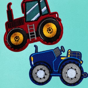 May include: Two toy tractors, one red and one blue. The red tractor has a ladder on the side and yellow wheels. The blue tractor has gray wheels.