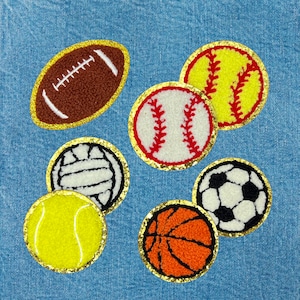 May include: A set of seven embroidered felt patches featuring various sports balls, including a football, baseball, basketball, soccer ball, tennis ball, and volleyball. The patches are all outlined in gold thread and have a fuzzy texture.