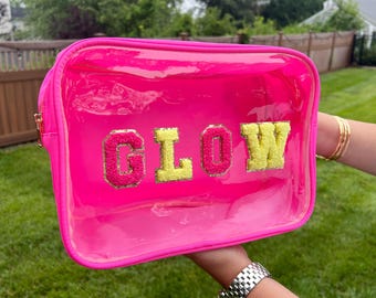 May include: A pink clear plastic zippered pouch with a fluffy yellow and pink "GLOW" design.