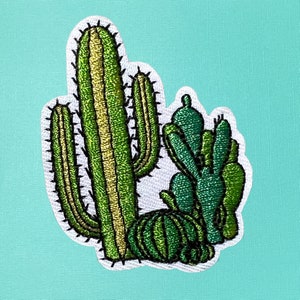 May include: A green embroidered cactus patch with a white background. The cactus is a tall, slender variety with a single stem and multiple arms. There are smaller cacti surrounding the main cactus.