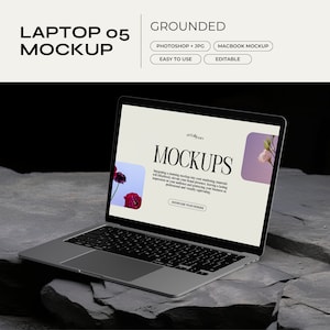 Op de afbeelding: Een zilveren laptop met een zwart toetsenbord is open op een grijs rotsoppervlak. Het laptopscherm toont een website met de tekst "Mockups" in wit lettertype. De achtergrond van de website is lichtblauw met een roze bloem in de rechterbovenhoek.