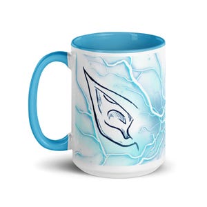 May include: A white ceramic mug with a blue rim and handle. The mug features a blue and white abstract design with a black outline of an elf ear.