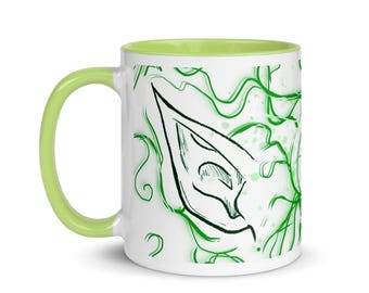 May include: White ceramic mug with a green and white design. The design features a stylized ear with a green outline and a white interior. The mug has a light green rim.