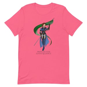 May include: A pink t-shirt featuring a graphic of a woman in blue armor holding a flag with green and white accents. The text "PRINCESS ESSIE ELVEN ALLIANCE" is printed below the graphic.