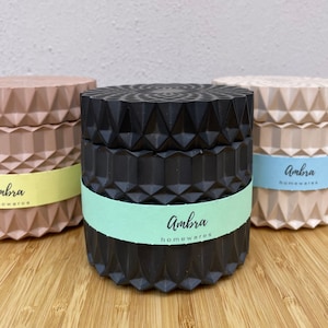 May include: Three geometric candle holders in black, beige and light pink with the text "Ambra Homewares" on the labels.