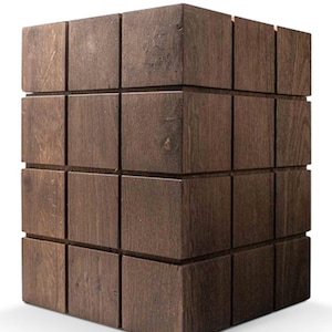 Op de afbeelding: Een donkerbruine houten kruk in de vorm van een kubus met een rasterpatroon op het oppervlak.