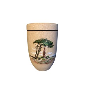 Puede incluir: Una urna beige con tapa, con una escena costera pintada a mano. La obra de arte representa un árbol verde, un faro y una zona de hierba. La urna tiene una forma suave y redondeada y una línea oscura donde la tapa se encuentra con el cuerpo.