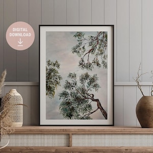 Op de afbeelding: Een digitale download van een aquarel schilderij van takken van een boom tegen een bewolkte lucht. Het schilderij is in tinten groen, bruin en grijs.