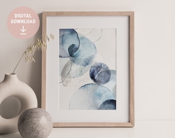 May include: Abstract watercolor art print in a wooden frame. The artwork features overlapping blue and gray circles with delicate lines. A digital download label is visible. A white vase and a gray sphere are in the foreground.