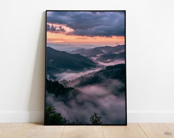 May include: A photograph of a mountain range with a layer of fog rolling through the valleys. The sky is a mix of purple, pink, and orange, with dark clouds in the distance.