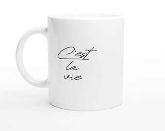 May include: White ceramic mug with black text that reads "C'est la vie".