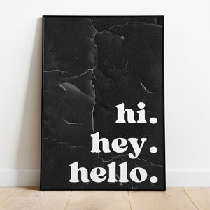 Könnte beinhalten: Schwarz gerahmter Kunstdruck mit den Worten "hi. hey. hello." in weißer, fetter Schrift. Der Hintergrund hat ein strukturiertes, rissiges Aussehen. Das Kunstwerk wird vor einer weißen Wand und einem Holzboden präsentiert.