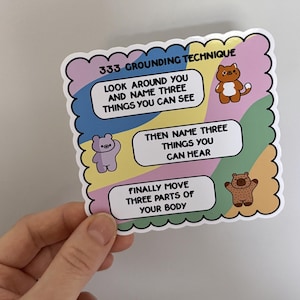 May include: A colourful sticker with a grounding technique. The sticker has a white border with rounded corners and features three steps: look around and name three things you can see, then name three things you can hear, and finally move three parts of your body. Each step is illustrated with a cartoon animal.