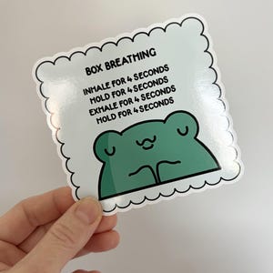 Może przedstawiać: Biała naklejka z zieloną żabą i tekstem "BOX BREATHING" oraz instrukcjami do oddychania pudełkowym: "INHALE FOR 4 SECONDS", "HOLD FOR 4 SECONDS", "EXHALE FOR 4 SECONDS", "HOLD FOR 4 SECONDS".
