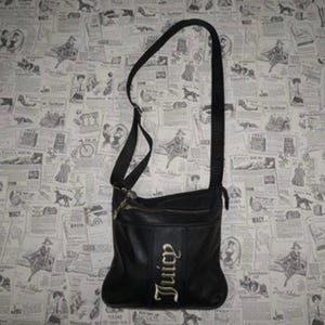 以下が含まれることがあります： 長いストラップが付いた黒いクロスボディバッグ。 バッグは上部にジッパーが付いており、前面パネルには「Juicy」の文字が金色のスクリプトで書かれています。 バッグは滑らかな素材でできており、長方形の形をしています。