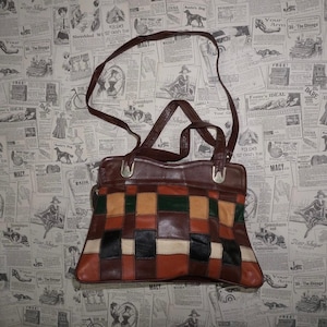 May include: A brown leather patchwork handbag with a shoulder strap. The bag features a variety of rectangular patches in shades of brown, black, green, and cream. The background is a vintage newspaper print.