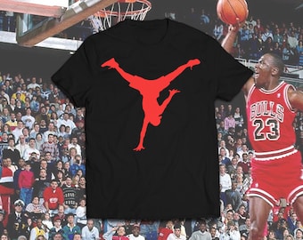 May include: Black t-shirt with a red silhouette of a basketball player doing a slam dunk. The player is upside down with their legs in the air.