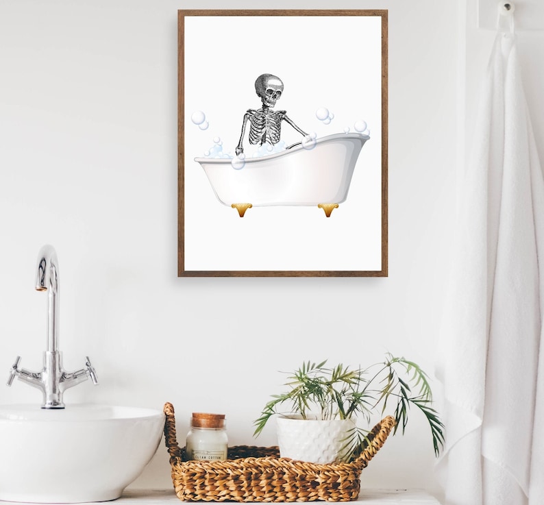 Puede incluir: Un esqueleto blanco y negro sentado en una ba&ntilde;era blanca con burbujas. La ba&ntilde;era tiene patas doradas. La imagen est&aacute; en un marco marr&oacute;n.