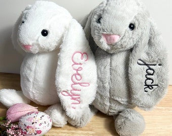 May include: Two plush bunny toys, one white with pink embroidery that says "Evelyn" and one gray with black embroidery that says "Jack".