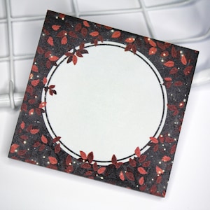 Peut inclure: Une carte noire et blanche avec un cercle rouge et blanc au centre. Le cercle est entouré d'une bordure de feuilles rouges sur un fond noir. La carte a une texture scintillante.