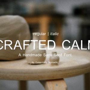 May include: A close-up of a font design called "Crafted Calm", a handmade sans serif font, with the words "regular | italic" above the font name and the words "A Handmade Sans Serif Font" below the font name. The words "by Essentially Nomadic" are below the font description. The font is displayed on a wooden surface with two small ceramic objects in front of the text.
