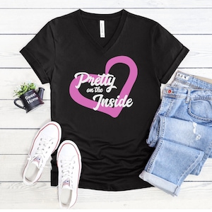 May include: Black v-neck t-shirt with a pink heart and the text "Pretty on the Inside" in white.