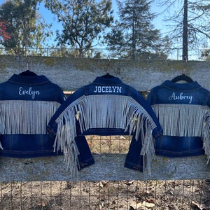 Puede incluir: Tres chaquetas vaqueras con pedrer&iacute;a y flecos. Las chaquetas est&aacute;n personalizadas con los nombres "Evelyn", "Jocelyn" y "Aubrey".