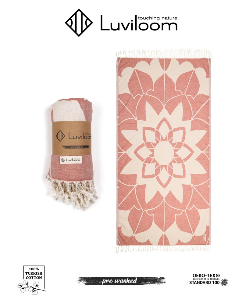 May include: A rectangular Turkish cotton towel featuring a terracotta and cream mandala pattern with tasseled ends. One towel is rolled and secured with a brown paper band labeled Luviloom, while the other is displayed flat to show the full design.