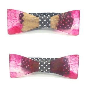 Può includere: Due papillon in resina rosa e bianca con un centro in legno e tessuto a pois neri e bianchi.