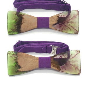 Può includere: Un papillon in legno con intarsi in resina verde e viola. Il papillon è attaccato a un cinturino regolabile viola.