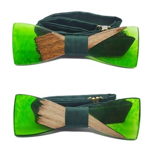 Può includere: Un papillon verde e marrone con un accento in legno. Il papillon è realizzato in resina e presenta una combinazione di colori verde e marrone. Il papillon è legato con un nastro verde scuro.