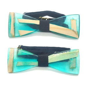 Può includere: Un papillon blu turchese con intarsi in legno. Il papillon è realizzato in resina e ha un cinturino regolabile nero.