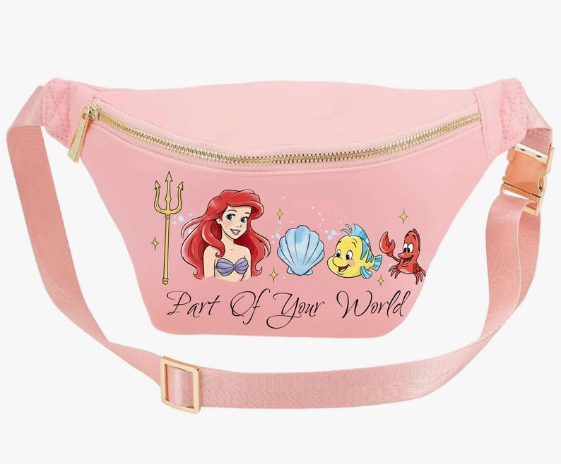 May include: Pink fanny pack with a gold zip and buckle. The pack features a graphic of Ariel, Flounder, Sebastian, and a seashell, with the text "Part of Your World". The adjustable strap is also pink.