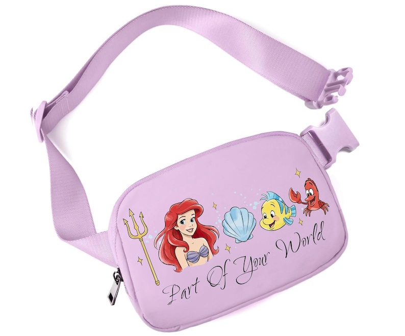 May include: A lilac fanny pack with a matching adjustable strap and buckle. The pack features a graphic of Ariel, Flounder, Sebastian, and a seashell. The text "Part Of Your World" is printed on the front.